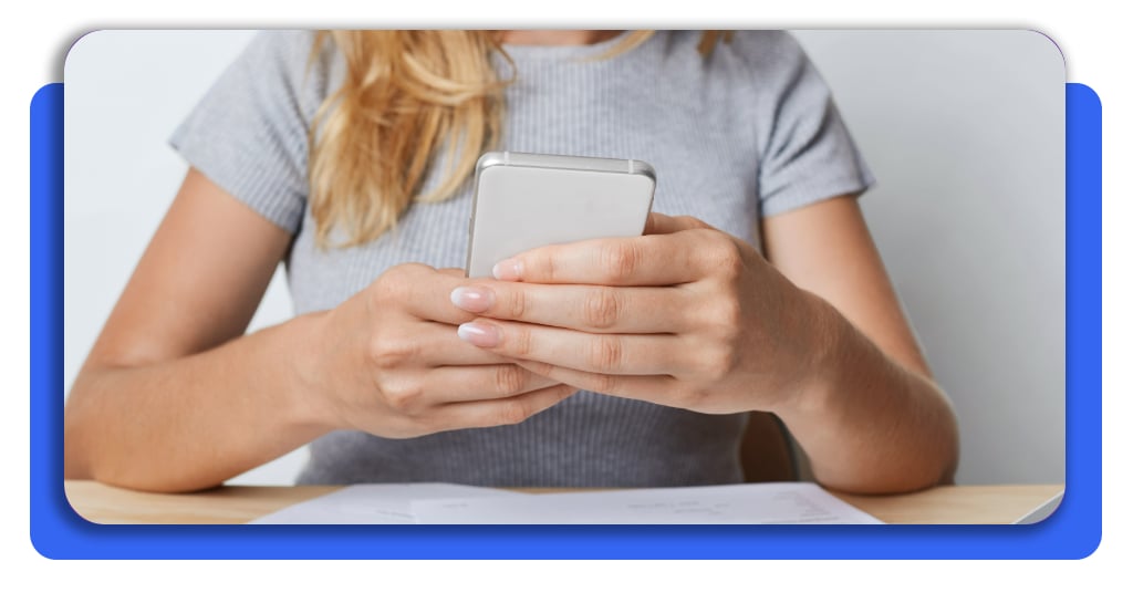 Mujer utilizando su teléfono en la oficina para consultar información en línea y gestionar de manera cómoda los servicios del hogar desde cualquier lugar